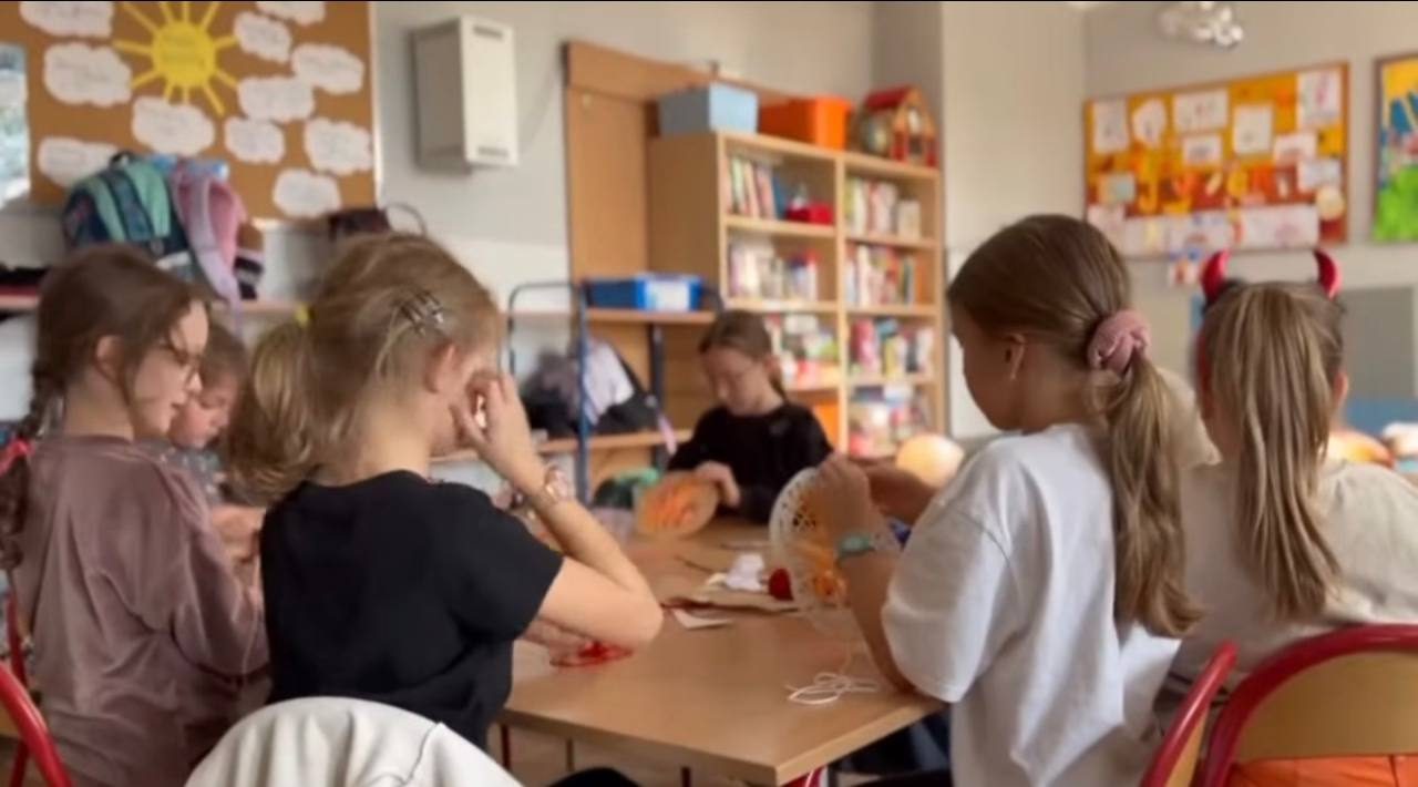 Dzieci wyplatają włóczką na papierowych talerzykach